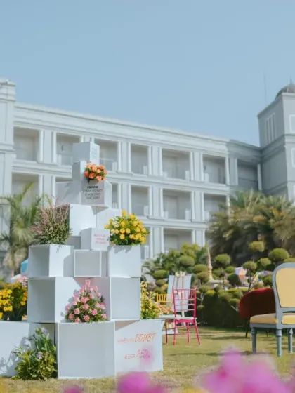 A modern, geometric installation of white blocks, used to display floral arrangements and personalized notes, adds an artistic touch to the garden setting.