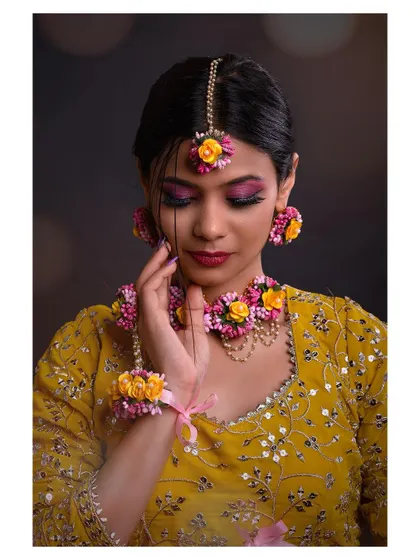 A close-up shot of a model in a festive yellow lehenga. The focus is on the intricate floral jewelry and the beautiful makeup.