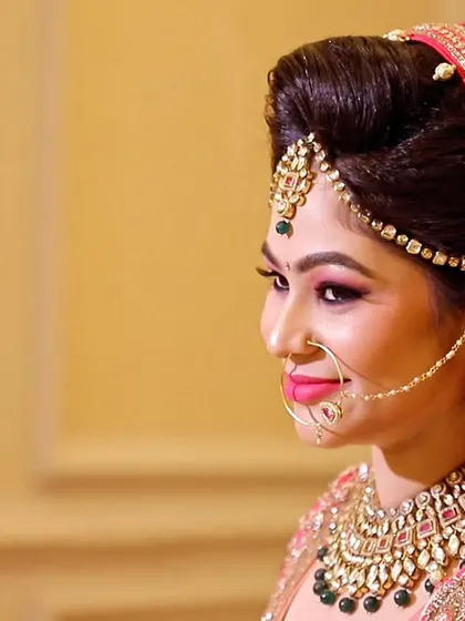 A side-profile portrait of a bride, showcasing her intricate hairstyle, makeup, and jewelry.