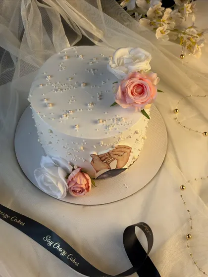 A wider view of the 25th-anniversary cake, showing the soft, romantic aesthetic created with a sheer backdrop and our signature ribbon.