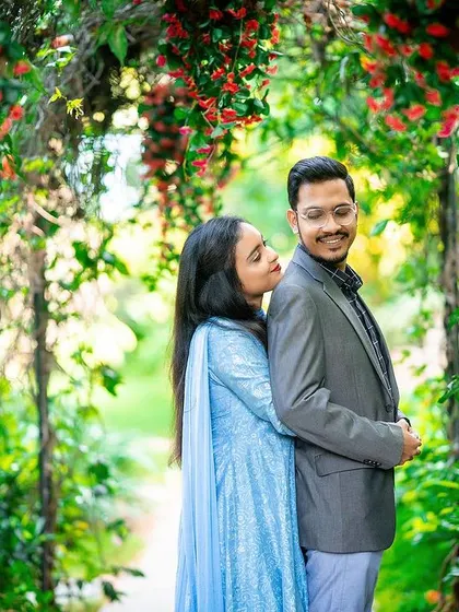 A sweet and romantic moment captured under an arch of red flowers.