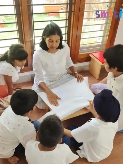 A teacher explains the significance of the khadi cloth to a group of children before they begin their flag-making activity.