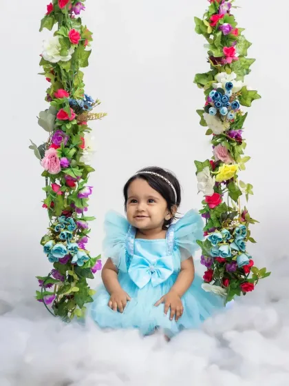 A serene portrait of the birthday girl on her floral swing, looking like a true princess.