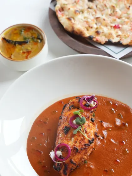 A complete meal featuring our Stuffed Chicken Breast, served alongside our house-made dal and a fluffy, freshly baked naan.