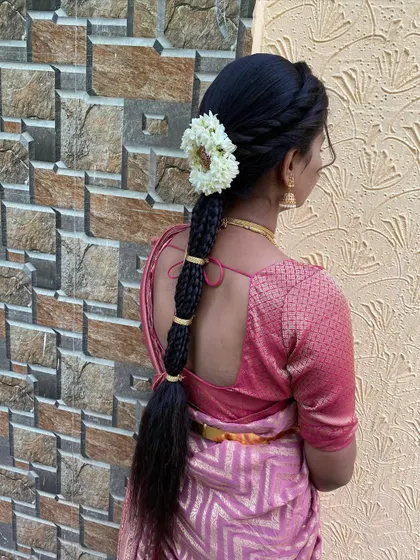 A simple yet elegant hairstyle with a twisted crown leading into a long braid. The look is finished with a side arrangement of fresh jasmine flowers.