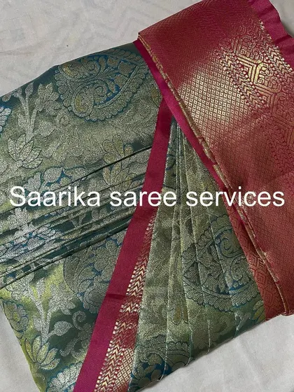 This grey-green saree with a pink border has a subtle elegance. The pleats are set for a perfect drape.
