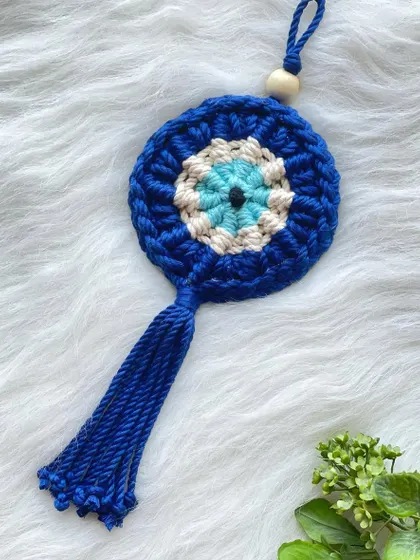 This overhead view shows the texture and detail of the knotting in the Evil Eye charm. It's small enough to be used as a car charm or a bag accessory.