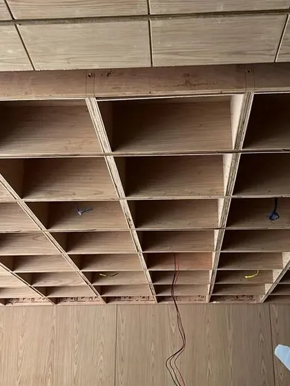 A work-in-progress shot showing the intricate construction of the wooden waffle ceiling. This detail showcases the level of craftsmanship that goes into creating such a unique and transparent architectural feature.