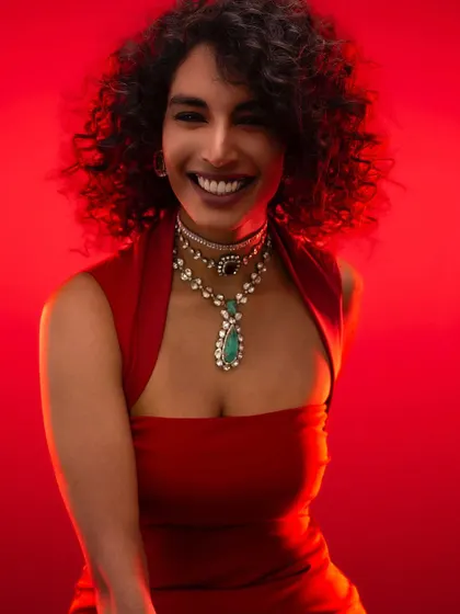 Mastering color and light is fundamental. Here, a bold red background makes the subject and her exquisite jewelry come alive. We practice using color theory and precise lighting to create vibrant, impactful portraits that command attention.