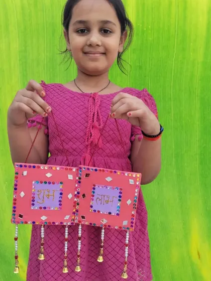 This young artist proudly holds up her handmade "Shubh Labh" wall hanging. Our Diwali craft sessions are a great way for kids to create beautiful decorations for their homes.