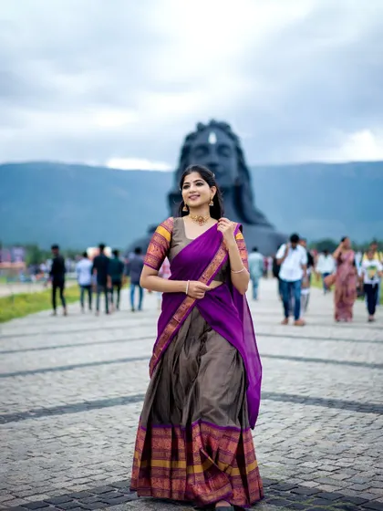 A spiritual moment at the Adiyogi statue, wearing a purple and grey half-saree. This image connects the traditional attire with a powerful symbol of divinity and inner peace.