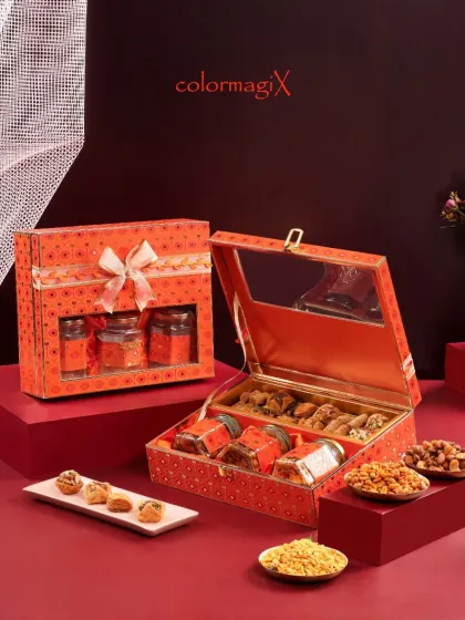 An open view of our orange patterned gift box, revealing a curated selection of dry fruits, nuts, and traditional Indian snacks. The clear window on the lid adds a touch of modern design.