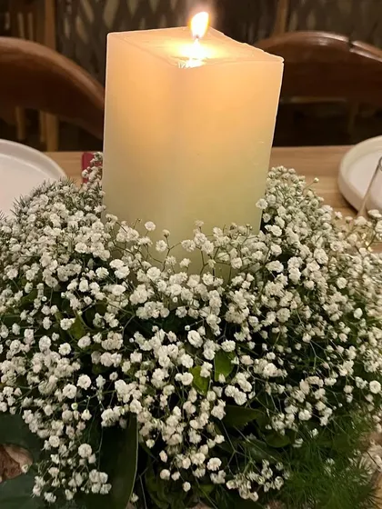 Ambiance is created through thoughtful details. This centerpiece, featuring a block candle nestled in a bed of baby's breath on a rustic wood slice, added a warm and romantic glow to each table.