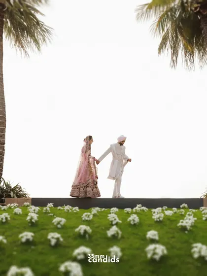 A creative, low-angle shot of the couple walking hand-in-hand, framed by palm trees. This perspective adds a unique and grand feel to their wedding portrait.