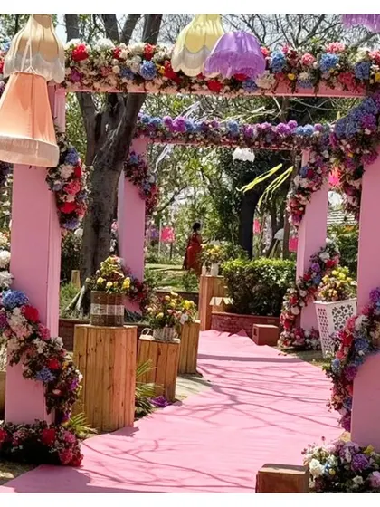 A closer look at the floral-laden entrance pathway. The pink arches are wrapped in multi-colored flowers, and hanging lamps of different shapes and colors add a playful touch.