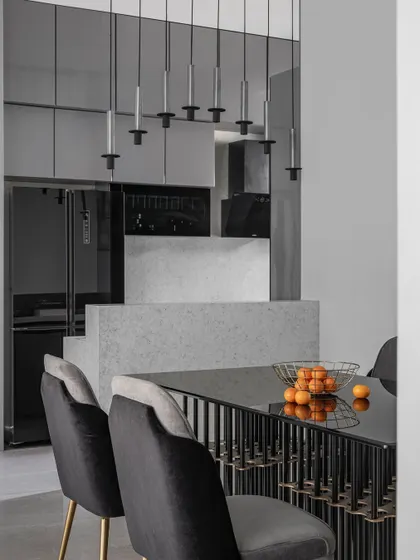 The dining area is a blend of luxury and functionality, featuring a grand table with a sleek glass top and chairs in plush fabric. The layout ensures a seamless connection to the kitchen for easy serving.