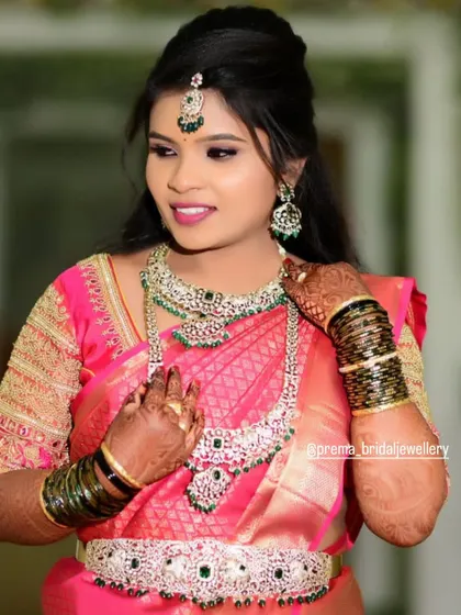 This bride looks gorgeous in a pink saree, complemented by an AD and emerald stone set.