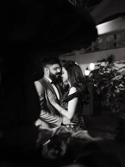 A moody and romantic black and white portrait of the couple near a fountain at night.