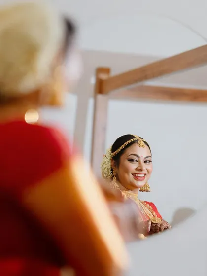 The bride smiles at her reflection in the mirror, a happy moment during her getting-ready process.