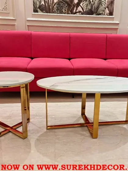 I believe in using bold color to bring energy to a space. This vibrant pink sofa creates a stunning contrast against the neutral walls with classic molding, while the nesting marble and steel coffee tables add a touch of modern elegance.