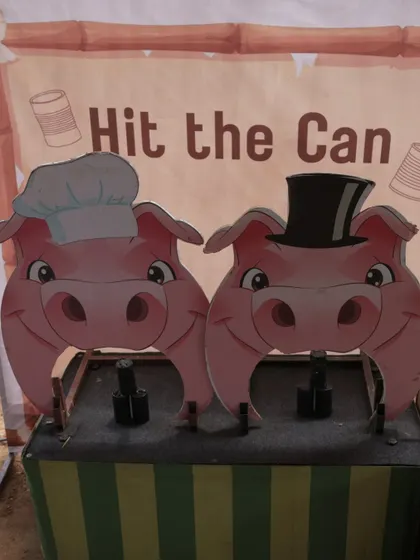An interactive "Hit the Can" carnival game with cute pig characters provided classic, fun entertainment for guests at the farm party.