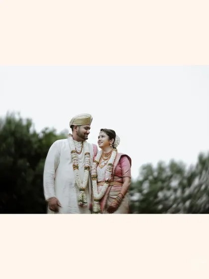 A wide shot of the couple looking at each other, framed against a soft, out-of-focus background of trees.