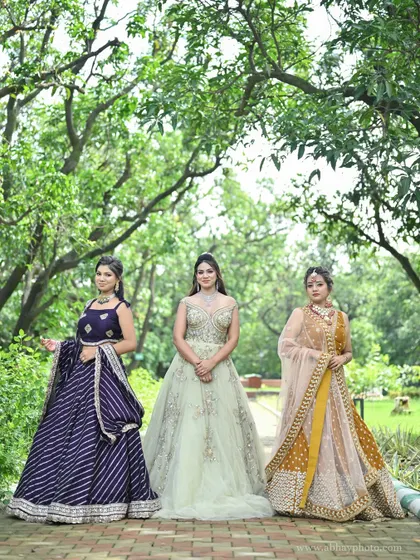 Our festive collection on display. This photo features three models wearing a purple leheriya lehenga, a pastel green gown, and a mustard yellow lehenga, showing different styles for various events.