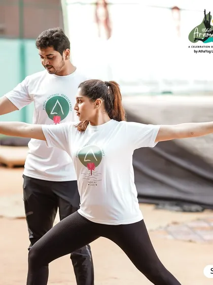 A teacher provides a gentle adjustment to a participant in Warrior II pose (Virabhadrasana II) during Yoga Arambha. We focus on providing guidance to ensure a safe and effective practice for everyone.