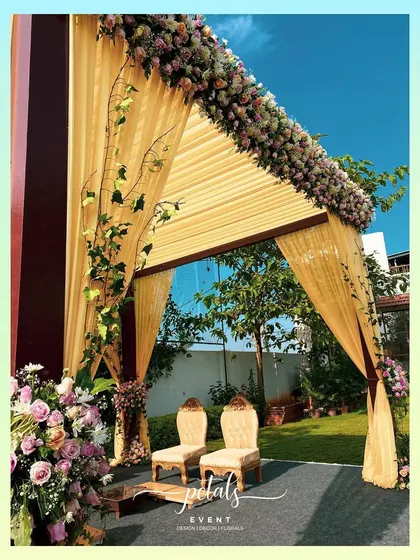 A side view of the contemporary mandap, showcasing the beautiful floral arrangements and the way the yellow drapes catch the sunlight. It's a perfect blend of modern style and romantic charm.
