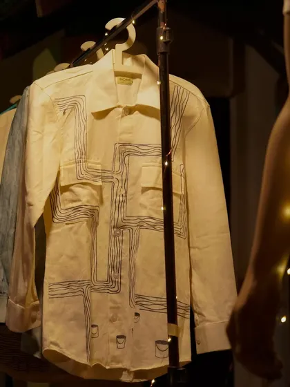A closer look at one of our hand-painted shirts. The intricate line work is done with natural dye paste, creating a wearable piece of art that is both stylish and sustainable.