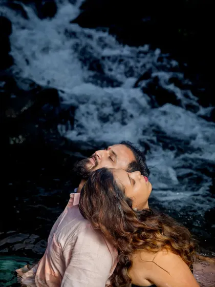 A serene moment of togetherness, with the couple leaning back against the rocks of the waterfall. This image evokes a sense of peace and deep connection.
