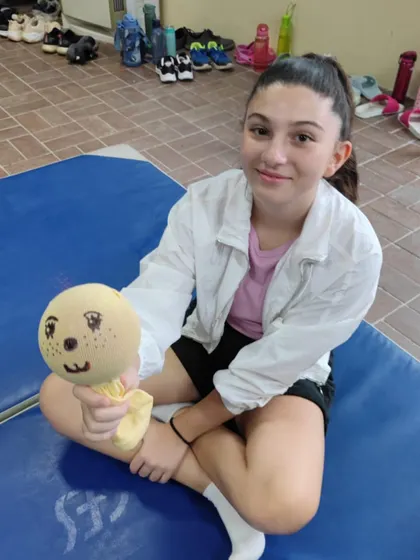 A happy student holds up her finished puppet. The smile on her face is the best reward for me as a teacher.