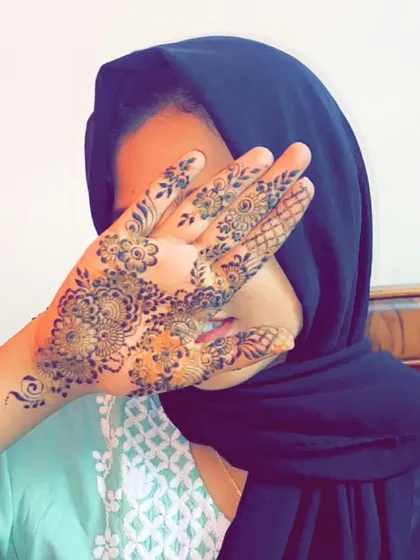 A beautiful shot of a client hiding playfully behind her freshly done henna. The simple floral pattern is elegant and perfect for any occasion.