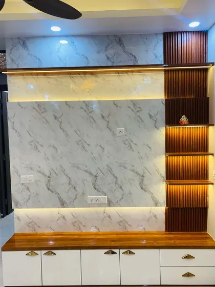 A detailed shot of the TV unit. The combination of a white marble panel, wooden top, and vertical fluted shelves with lighting creates a warm and modern aesthetic.