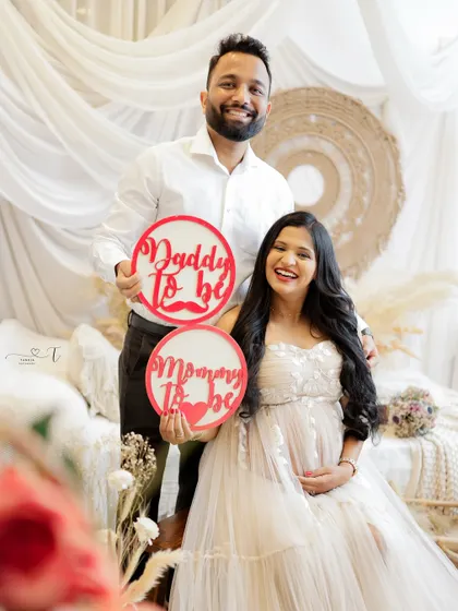 "Mommy to be" and "Daddy to be." This couple uses cute signs to announce their new roles in a beautifully styled studio setting.