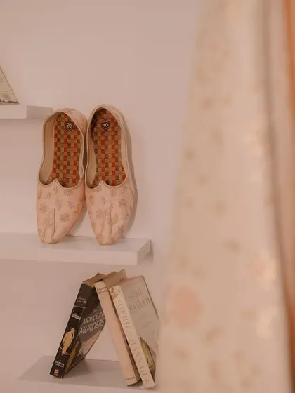 An artistic shot of the groom's traditional shoes (juttis) placed on a shelf, a small but significant detail of the wedding preparation.