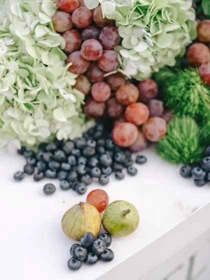 A quiet celebration of abundance. This tablescape for a sit-down dinner features soft ivories and nature's own palette, with blueberries, figs, and Australian grapes nestled among fresh greens.