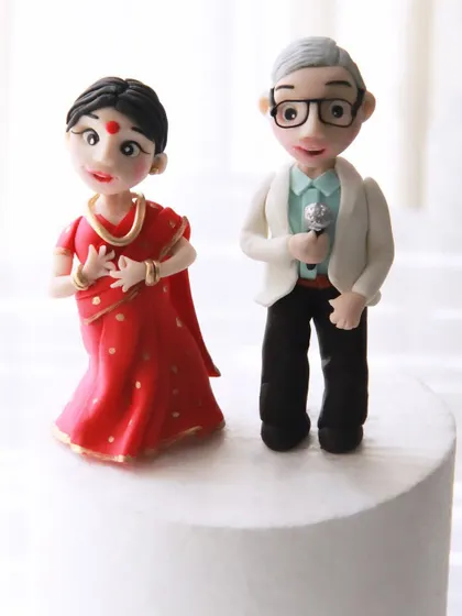 A close-up of the custom toppers for the 25th anniversary cake, showing the husband with his microphone and the wife in a dancing pose, all handcrafted from fondant.