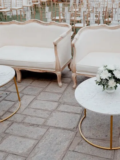 Elegant lounge seating for guests at the Sangeet, with white sofas and marble-topped tables.