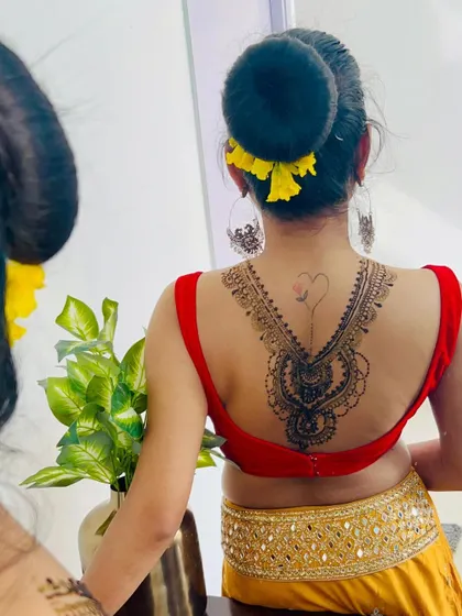 The client admiring her back henna in the mirror. This type of design is a bold and beautiful choice for a special occasion.