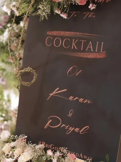 A stylish welcome sign for Karan and Priyal's cocktail party, designed with a modern font and framed with beautiful flowers.