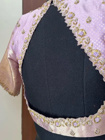 The back of our pastel lilac blouse, showcasing a unique cutout design framed with delicate, scalloped zardosi embroidery.