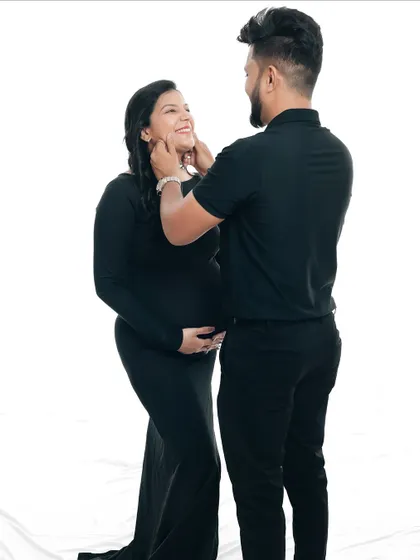 A tender moment between the couple, dressed in matching black outfits. The partner gently holds his wife's face as they share a loving gaze.