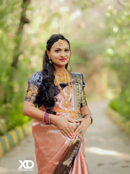 A beautiful solo portrait focusing on the mother-to-be, dressed in a stunning silk saree and traditional gold jewelry.