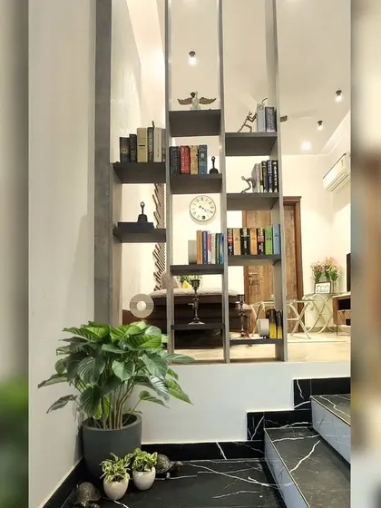The concrete-finished bookshelf partition in the Monochrome Oasis lounge serves as both a functional storage unit and a modern design element.