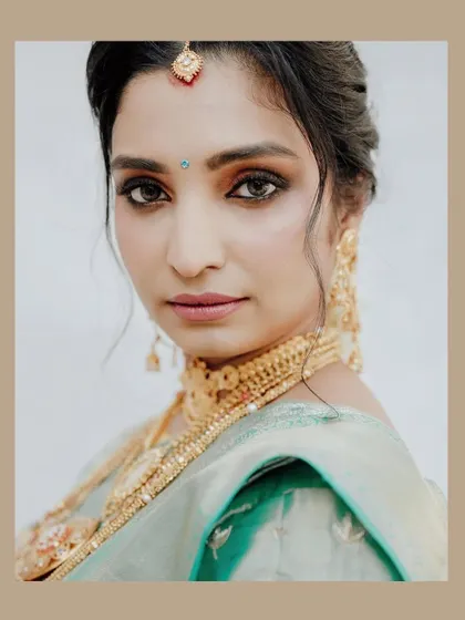 A stunning close-up portrait of a South Indian bride, highlighting her beautiful makeup and traditional gold jewelry.