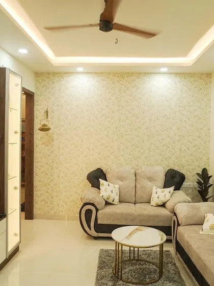 This cozy living room is perfect for family time, featuring a comfortable sectional sofa and a TV unit with integrated display shelves. The patterned wallpaper adds a subtle layer of texture and personality.