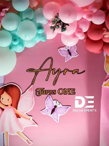 A close-up of the backdrop for Ayra's fairy party, showing the custom name sign and cute character cutouts.