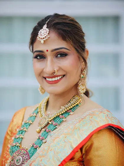 A classic South Indian look featuring a warm, glowing complexion and a traditional red bindi. The makeup is designed to harmonize with the beautiful green and gold tones of the pattu saree and temple jewelry.