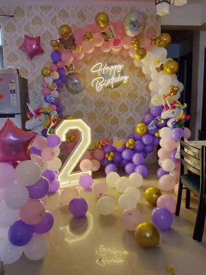 A unicorn-themed second birthday with a circular balloon arch and a light-up number '2'.